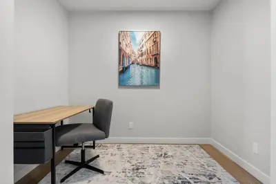 a desk with a chair and a painting on a wall at Bright & Spacious 3 Beds Luxury Home in SE Calgary in Calgary