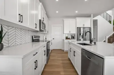 a white kitchen with white cabinets and a sink at Bright & Spacious 3 Beds Luxury Home in SE Calgary in Calgary
