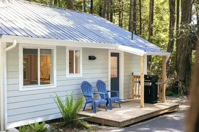 two blue chairs on the porch of a tiny house at Surfs Inn Guesthouse & Cottages in Ucluelet