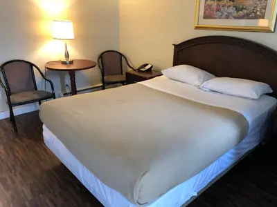 a bed in a hotel room with two chairs and a table at Travellers Inn in Calgary
