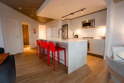 a kitchen with white cabinets and red bar stools at High rise Apartment in Vancouver