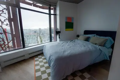 a bedroom with a bed and a large window at High rise Apartment in Vancouver