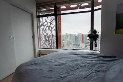 a bedroom with a bed and a large window at High rise Apartment in Vancouver