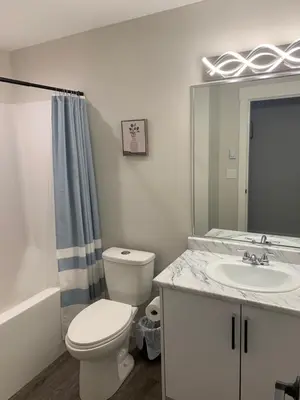 a bathroom with a toilet and a sink and a mirror at Entire 2BR Guest House in Quiet Area in Nanaimo