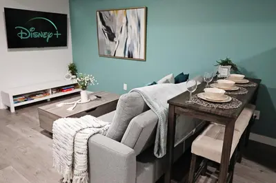 a living room with a table with a chair and a couch at Beautiful Home With 4 King Beds,Airport,Disney+ in Edmonton