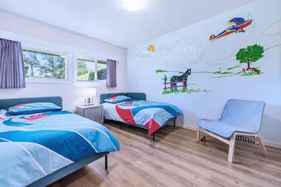 a bedroom with two beds and a chair at Three-Tree Villa-Central Location in Vancouver