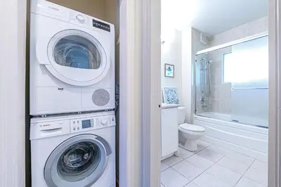 a bathroom with a washer and dryer next to a toilet at Three-Tree Villa-Central Location in Vancouver