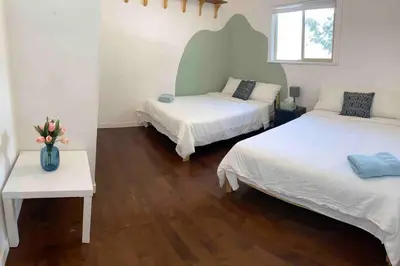 a bedroom with two beds and a vase of flowers on a table at Westside Pool Home-8 min to Downtown, Yard Parking in Vancouver