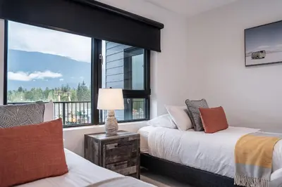 a bedroom with two beds and a large window at RevelStoked Getaway by Revelstoke Vacations in Revelstoke