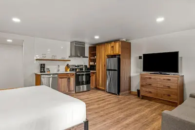 a room with a bed and a kitchen with a flat screen tv at Hotel Canoe and Suites in Banff