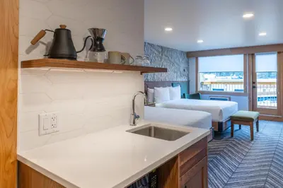 a kitchen with a sink and a room with two beds at Hotel Canoe and Suites in Banff