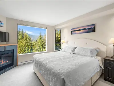 a bedroom with a large bed and a fireplace at Ski In/Out, Steam Shower, Pool, Hot Tub, Sauna in Whistler