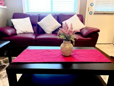 a purple couch with a vase of flowers on a table at Cozy Walkout suite with King bed, Kitchen, Parking & Patio in Calgary