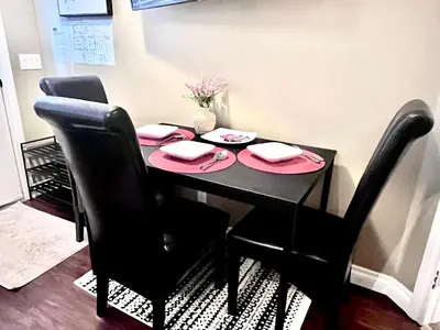 a black dining room table with black chairs and pink place settings at Cozy Walkout suite with King bed, Kitchen, Parking & Patio in Calgary