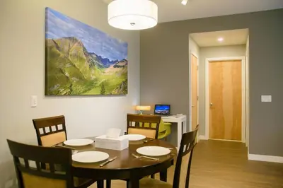 a dining room with a table and chairs and a painting at Bright Modern Stylish Condo in heart of Downtown (Center) in Whitehorse