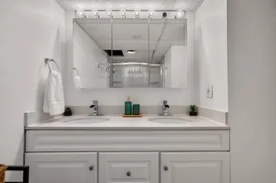 a bathroom with two sinks and a mirror at Downtown Near Rogers Place with Covered Parking, Sleeps 6, Pool Table, Sauna, Gym, Two Bedrooms & More in Edmonton
