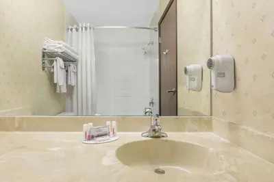 a bathroom with a sink and a mirror at Ramada by Wyndham Clairmont/Grande Prairie in Clairmont