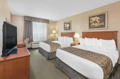 a hotel room with two beds and a flat screen tv at Ramada by Wyndham Clairmont/Grande Prairie in Clairmont