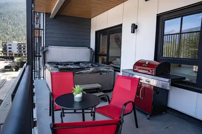 a patio with red chairs and a table and a grill at Alpine Haven by Revelstoke Vacations in Revelstoke
