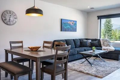 a living room with a table and a blue couch at Alpine Haven by Revelstoke Vacations in Revelstoke