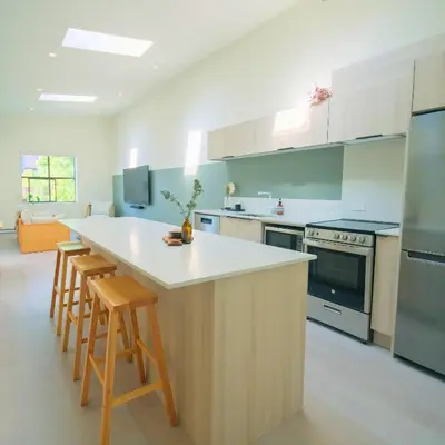 a kitchen with a white counter top and wooden stools at Newly Renovated 1 Bedroom Condo in Japantown! Near Gastown & Railtown! in Vancouver