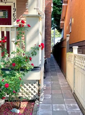 a house with a white gate and red roses at Private Guest Suite 10mins to Downtown - King Bed - Bathtub - Free Parking in Vancouver