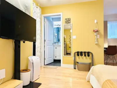 a bedroom with yellow walls and a flat screen tv at Private Guest Suite 10mins to Downtown - King Bed - Bathtub - Free Parking in Vancouver
