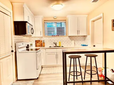 a kitchen with white cabinets and a table and stools at Scorpio House Langley -ROOM A in Langley