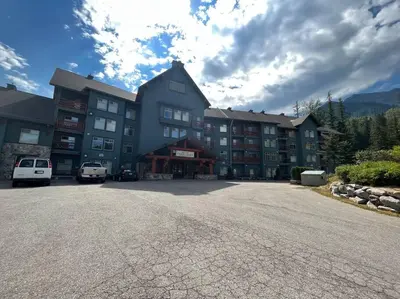 a large building with cars parked in front of it at Snow Creek Lodge by StayIn in Fernie