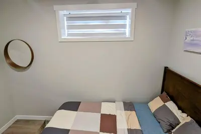 a bedroom with a bed with a mirror and a window at Cozy basement for a lovely stay & perfect for WFH in Edmonton