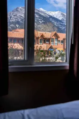a window with a view of a house and mountains at Mountain view walk to all in Canmore Canada in Canmore