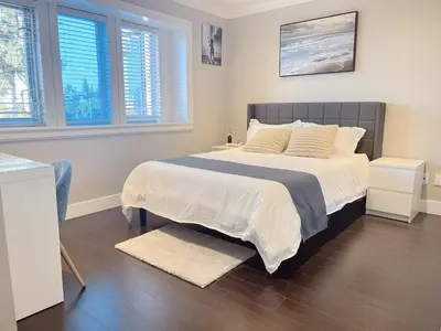 a bedroom with a large bed with white sheets and pillows at Near Skytrain and QUIET Private Bedroom Ensuite BathRM, Free Wifi & Coffee, Cozy in Burnaby