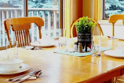 a wooden table with plates and utensils on it at Pine Cone Cabin by StayIn in Radium Hot Springs