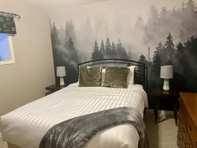 a bedroom with a bed with a forest mural on the wall at Pine Cone Cabin by StayIn in Radium Hot Springs