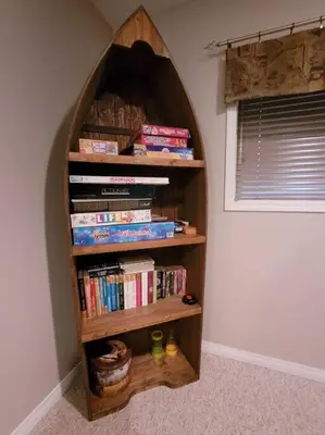 a book shelf filled with books next to a window at Pine Cone Cabin by StayIn in Radium Hot Springs
