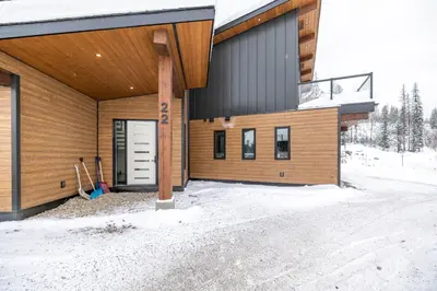a house with a wooden facade in the snow at 22 Sunniva by StayIn in Fernie