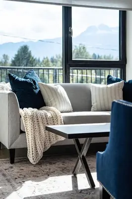 a living room with a couch and a table and a window at Stoked 4Ever - Revelstoke Condo (+Hot Tub) in Revelstoke