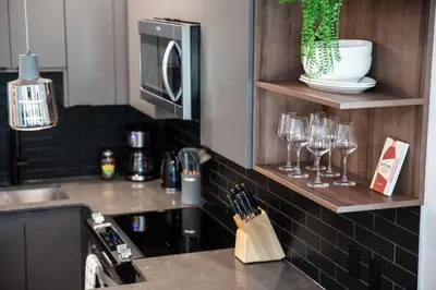 a kitchen with a counter with wine glasses on a shelf at Selkirk Powder Dream - Cozy Condo (+Hot Tub) in Revelstoke
