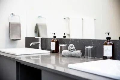 a bathroom counter with two sinks and bottles of alcohol at Selkirk Powder Dream - Cozy Condo (+Hot Tub) in Revelstoke