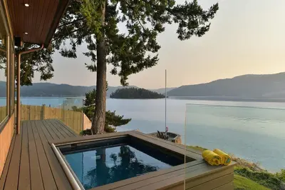 a swimming pool on a deck next to the water at Island Luxury Oceanside Estate by EMR Vacation Rentals in Saanichton