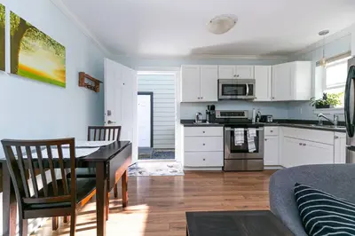 a kitchen with white cabinets and a table in a room at Great 1-bedroom Suite Near Downtown Langford in Victoria