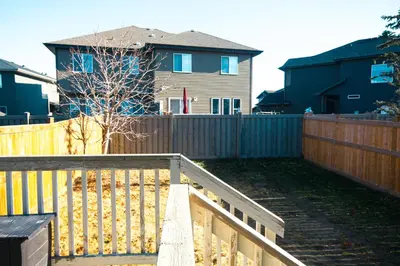 a wooden fence in a yard with a house at Entire Home AC 4Beds Sleeps 8 Double Garage Near WEM Free Wifi & Netflix in Edmonton