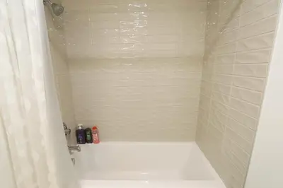 a bathroom with a shower with a white tub at Vibrant & Modern Loft-style Walkout Near LRT in Calgary