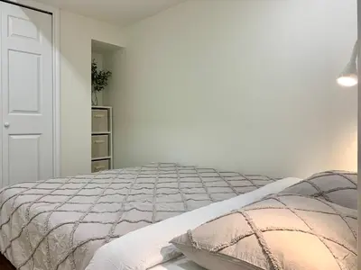a white bedroom with a bed and a white door at 3Beds 2BA Cherry Blossom Suite - Free Parking - Central Oakridge Neighbourhood in Vancouver