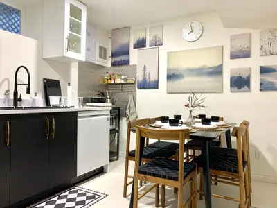 a kitchen with a table and chairs and a clock on the wall at 3Beds 2BA Cherry Blossom Suite - Free Parking - Central Oakridge Neighbourhood in Vancouver