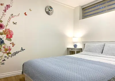 a bedroom with a bed and a clock on the wall at 3Beds 2BA Cherry Blossom Suite - Free Parking - Central Oakridge Neighbourhood in Vancouver