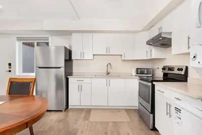 a kitchen with white cabinets and a wooden table at William Place in Surrey