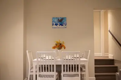 a white table with white chairs and a vase with flowers at Creek Side 2-Bedroom Guest Suite in Burnaby
