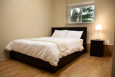 a bedroom with a large bed with a window at Creek Side 2-Bedroom Guest Suite in Burnaby