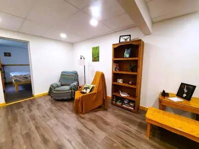 a living room with a chair and a book shelf at Woodcrest Bed and Breakfast in Clearwater